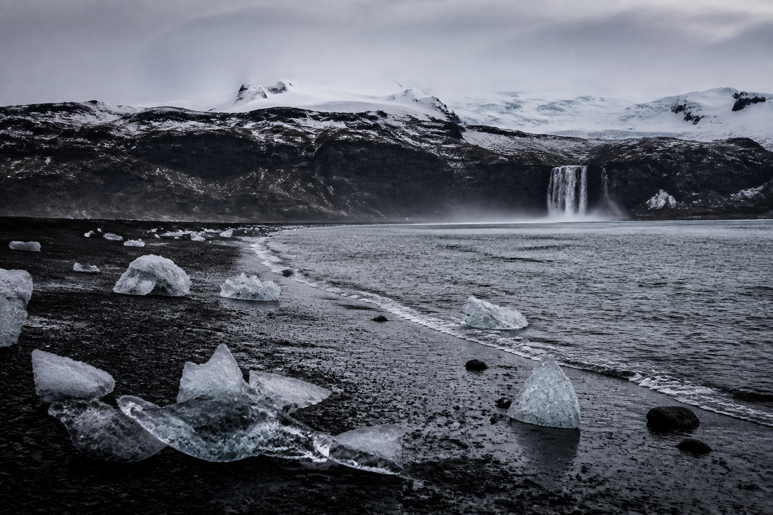 Volcanic winter coast, ice and distant mountains
